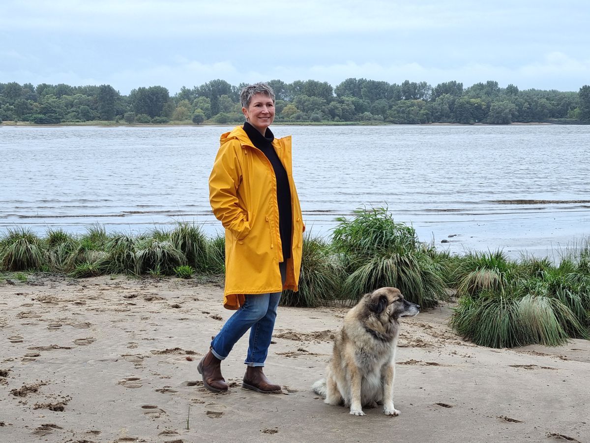 Ines Meyrose – Outfit 2021 – Rollkragenpullover dunkelblau, Jeans blau, Chelseaboots braun, Regenjacke gelb - Ü50 Bloggerin mit Hund Paul