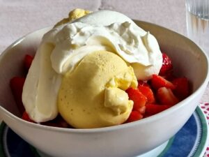 Eisbecher mit selbst gemachtem Vanilleeis auf Erdbeeren und Schlagsahne