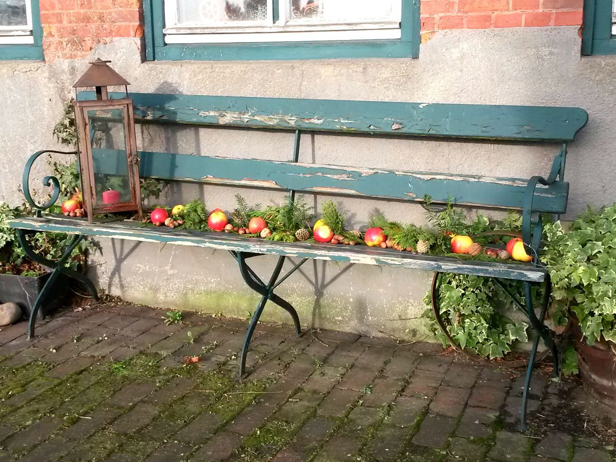 Herbstlich dekorierte Bank mit Äpfeln, Zweigen und Nüssen