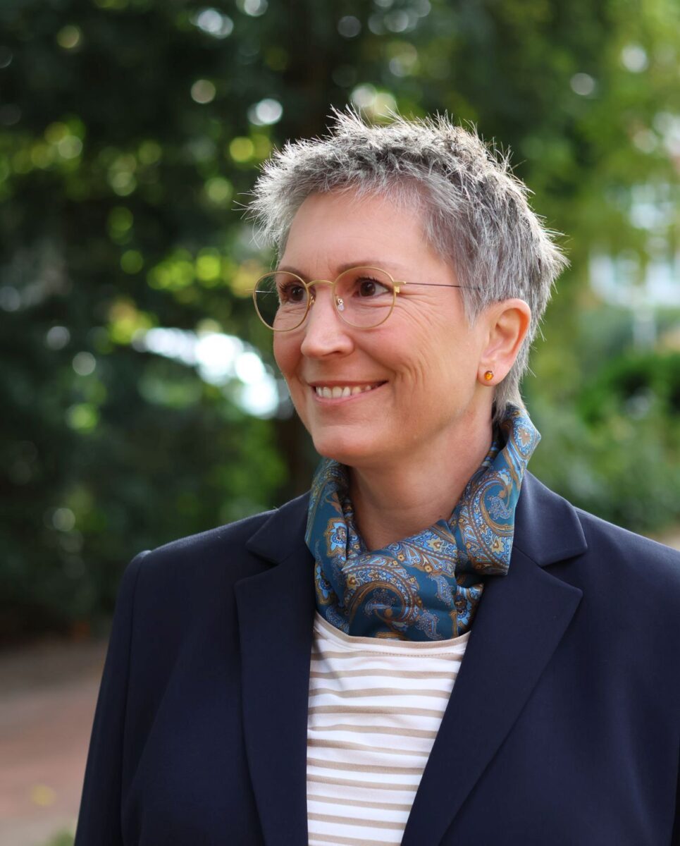 Ines Meyrose - Outfit 2023 mit dunkelblauem Blazer, blauer Jeans mit leichter Waschung, Ringelshirt in Hellbraun-Natur und Seidenschal in Petrol mit Paisleymuster - Farbklammer Braun und Blau - Portrait - Foto Nicole