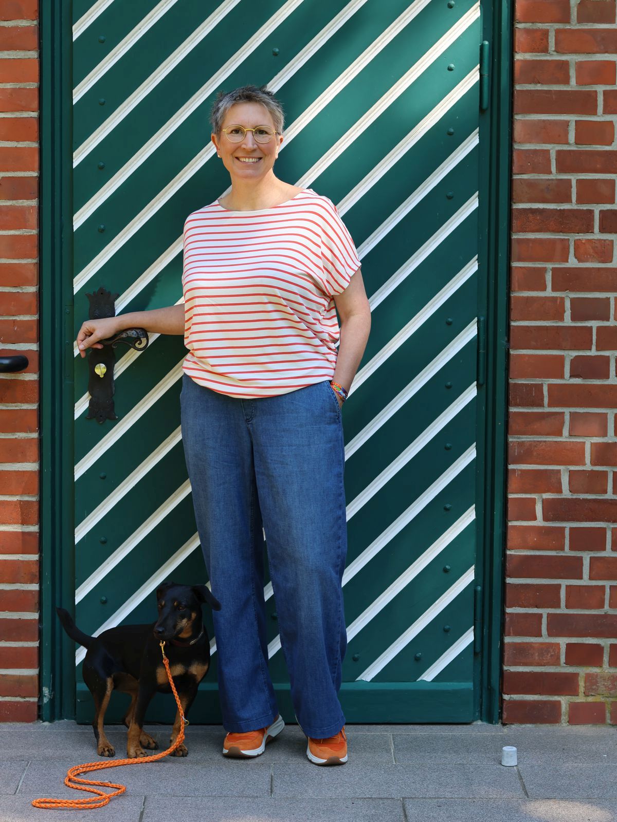 Ines Meyrose - Outfit 2025 - Ringelshirt in Orange-Cremeweiß - weite Sommerjeans in Blau - Sneaker Orange - Seidentuchstreifen als Armband - mit Hund Mona - Foto Nicole