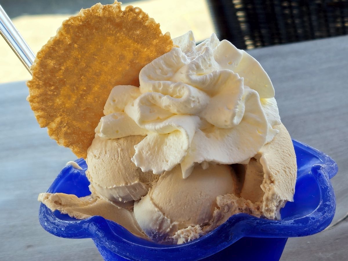 Eisbecher - Haselnusseis mit Sahne und Waffel in einem blauen Glasbecher