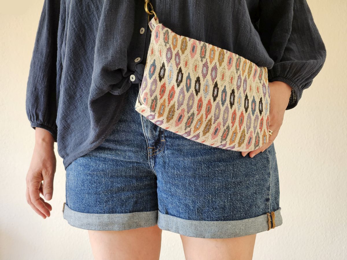 Ines Meyrose - Outfit 2026 - Sommer - Jeansshorts, blaue Tunikablause, mittelgroße Stofftasche bunt mit messingfarbenen Beschlägen