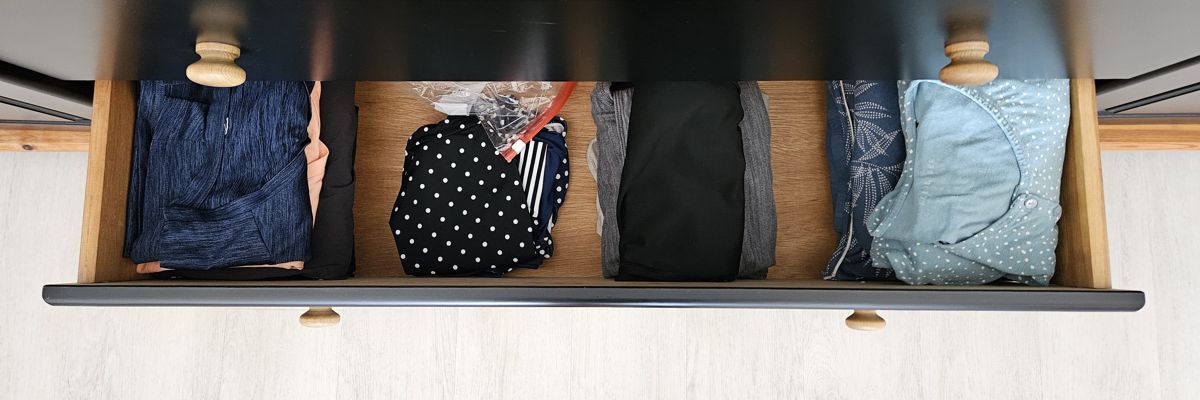Kleidung liegend gefaltet und in Stapeln in einer Schublade aufbewahrt.