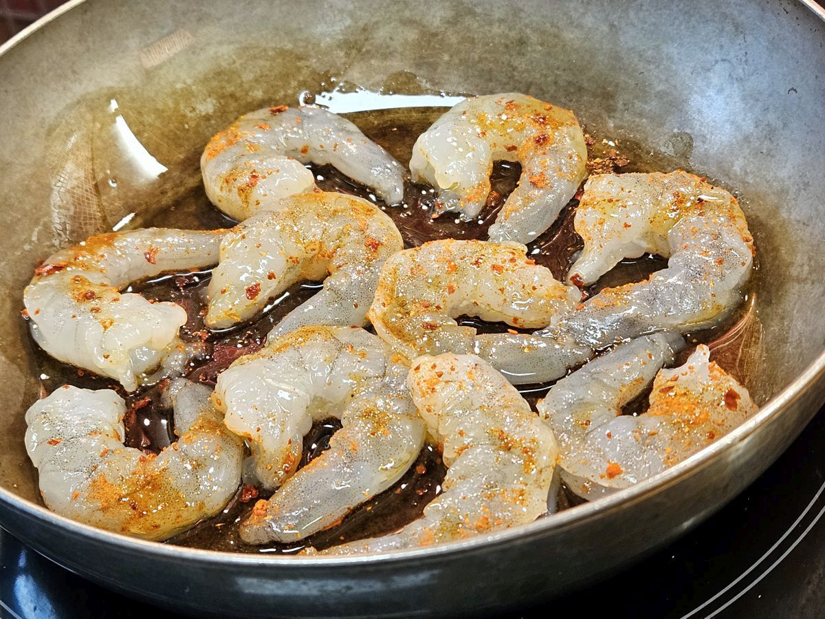 Scampi roh in mit Harissa gewürztem Olivenöl in einer Eisenpfanne
